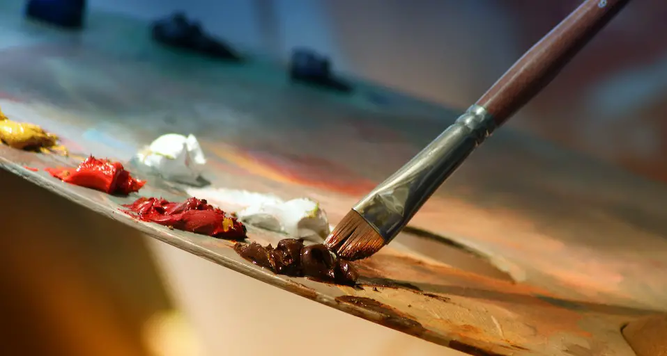 Photo of a painter's palette with a brush mixing oil paint