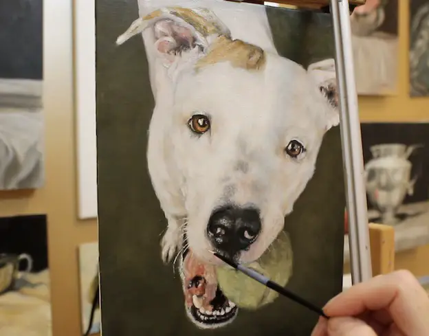 Painting the whiskers on a pet portrait painting of a pit bull.